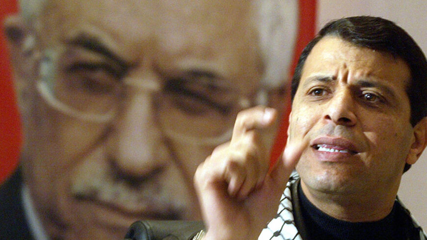 RAMALLAH, :  Palestinian outgoing cabinet minister and Fatah leader Mohammed Dahlan speaks in front of a portrait of Palestinian Authority President Mahmud Abbas during a press conference he held in the West Bank city of Ramallah 15 January 2006. Israel gave its approval for Arab residents of annexed east Jerusalem to vote in this month's Palestinian election but made clear it would not tolerate campaigning by Islamic militant group Hamas. AFP PHOTO/ABBAS MOMANI  (Photo credit should read ABBAS MOMANI/AFP/G