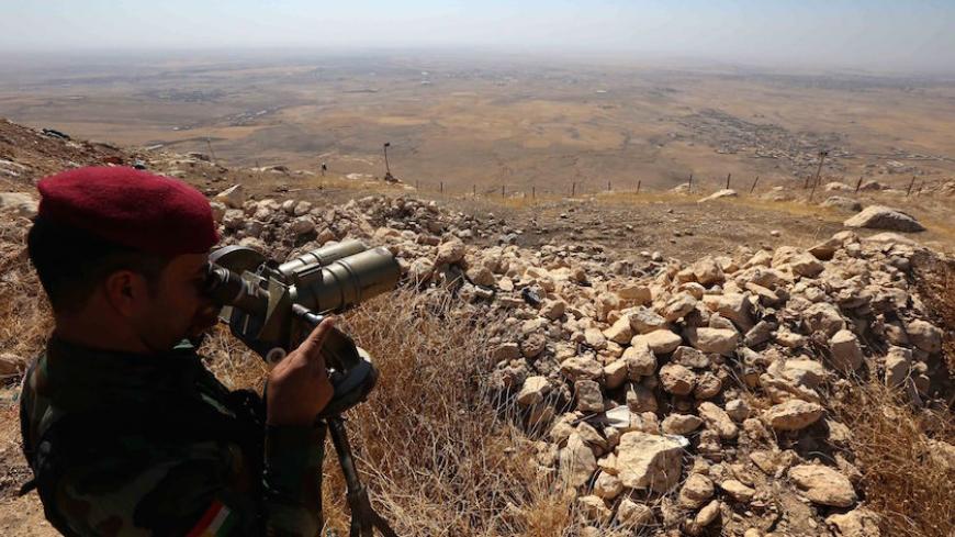 An Iraqi Kurdish Peshmerga fighter looks through binoculars on the top of Mount Zardak, about 25 kilometres east of Mosul, on October 6, 2016. 
Mosul, Iraq's second city, was seized by the Islamic State (IS) group in 2014 after multiple Iraqi divisions collapsed in the face of a jihadist assault.
But Baghdad is now planning, with help from a US-led coalition, a major operation to retake the city, which had a population of two million before the IS invasion.  / AFP / SAFIN HAMED        (Photo credit should r