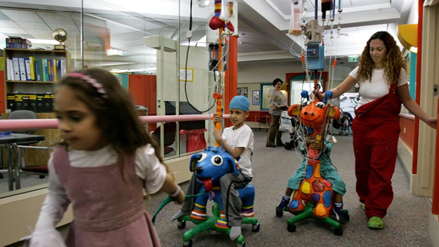 Amit (2nd L), a 7 year old cancer patient, sits on his intravenous drip stand decorated with an animal figure at Schneider Children's Medical Center in Petah Tikva March 23, 2006. The hospital offers art therapy for children undergoing cancer treatments as a way to make their treatments more friendly. REUTERS/Ronen Zvulun - RTR17JJ2