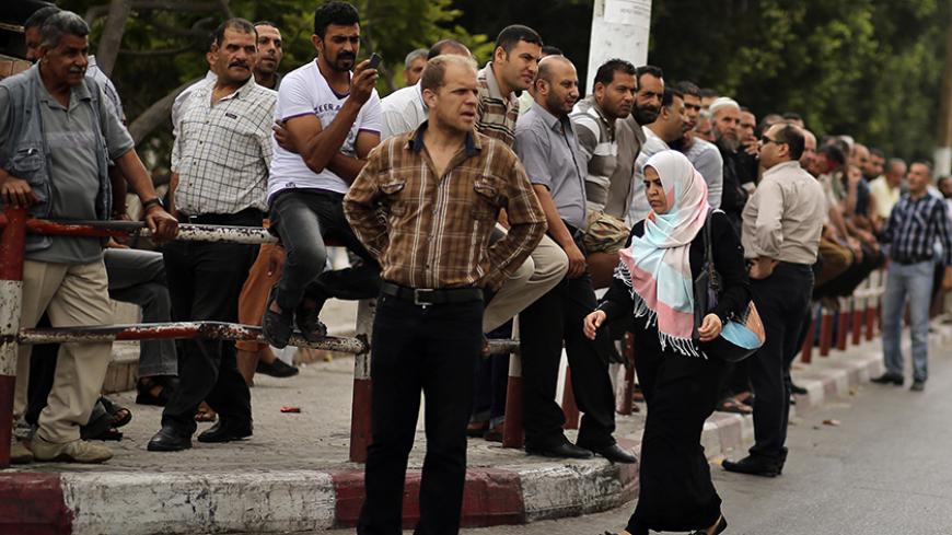 Palestinian employees paid by the Palestinian Authority wait to receive their salaries outside a closed bank after a scuffle with employees appointed by Hamas since 2007, in Gaza City June 5, 2014. A Palestinian unity government formed by President Mahmoud Abbas and the Islamist Hamas group faced its first and serious challenge on Thursday when civil servants of Hamas, who were not on a payment list, scuffled with those cashing their salaries. Civil servants employed by Hamas since 2007 arrived and prevente