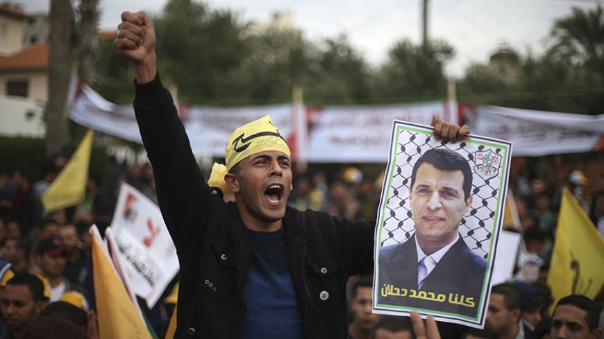 A Palestinian supporter of former head of Fatah in Gaza, Mohammed Dahlan, holds a poster depicting Dahlan during a protest against Palestinian President Mahmoud Abbas in Gaza City December 18, 2014. Dahlan, who lives in exile in the Gulf, is a powerful political foe of Abbas. 
REUTERS/Mohammed Salem (GAZA - Tags: POLITICS) - RTR4IJ7B