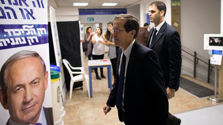 Isaac Herzog (C), co-leader of the Zionist Union party, walks past a Likud party campaign poster, that depicts Israeli Prime Minister Benjamin Netanyahu, as he arrives to address college students in Jerusalem March 10, 2015. REUTERS/Ronen Zvulun/File Photo - RTSEUAJ