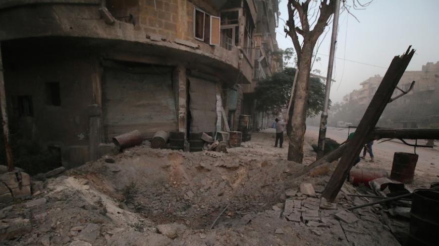 A man inspects damage near a hole in the ground after airstrikes on the rebel held al-Ansari neighbourhood of Aleppo, Syria October 2, 2016. REUTERS/Abdalrhman Ismail  - RTSQFXT