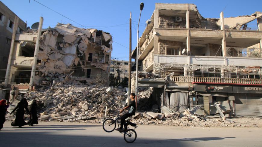 A boy plays with a bicycle past damaged buildings in the rebel held Seif al-Dawla neighbourhood of Aleppo, Syria October 6, 2016. REUTERS/Abdalrhman Ismail  - RTSR2TV