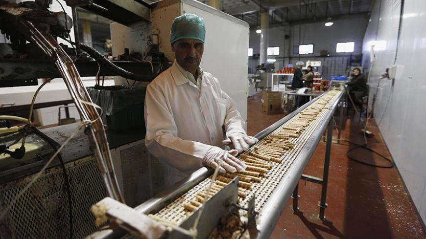 A worker stands near a conveyor belt at a chocolate and baked goods factory in the West Bank city of Ramallah October 27, 2013. The crackdown on the Gaza Strip as Egypt demolishes the smuggling tunnels along its sandy border, and stagnation in the West Bank mean the Palestinian economy might shrink this year after average annual growth of about nine percent in 2008-2011. To match Analysis PALESTINIANS-ECONOMY/    REUTERS/Mohamad Torokman (WEST BANK - Tags: POLITICS BUSINESS FOOD) - RTX14QCR