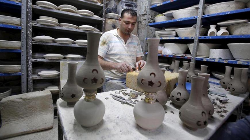 A Palestinian makes ceramic lamps used as decoration during the holy month of Ramadan in the old city of the West bank city of Hebron June 18, 2015. REUTERS/Mussa Qawasma - RTX1H2S8