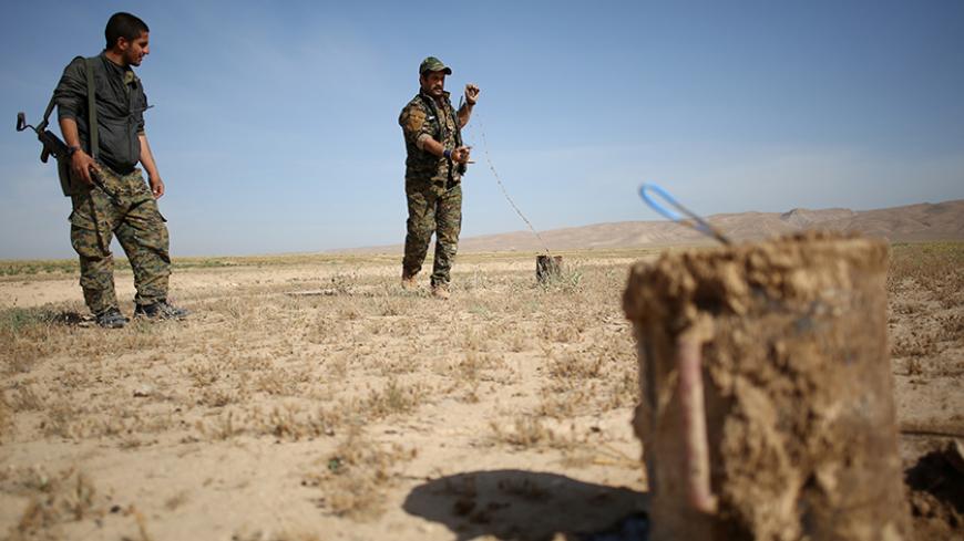 Members of the Sinjar Resistance Units (YBS), a militia affiliated with the Kurdistan Workers' Party (PKK), disarm an improvised explosive device placed by Islamic State fighters near the village of Umm al-Dhiban, northern Iraq, April 30, 2016. They share little more than an enemy and struggle to communicate on the battlefield, but together two relatively obscure groups have opened up a new front against Islamic State militants in a remote corner of Iraq. The unlikely alliance between the Sinjar Resistance 