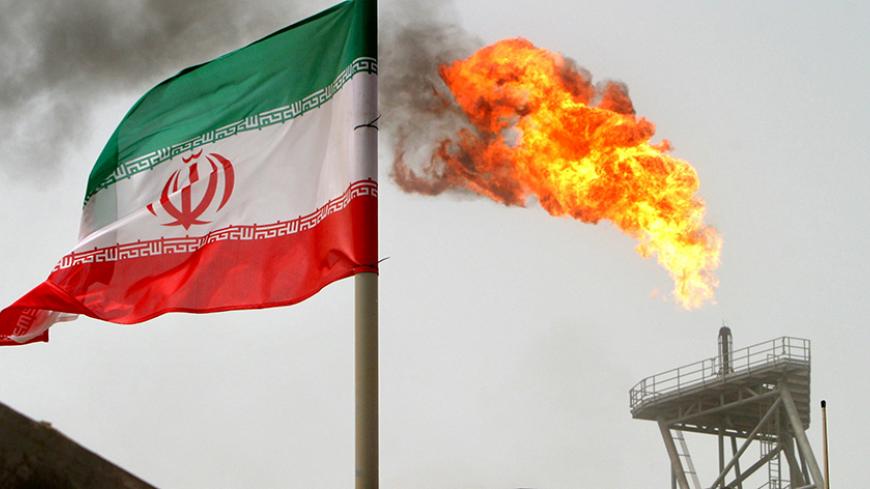 A gas flare on an oil production platform is seen alongside an Iranian flag in the Gulf July 25, 2005. REUTERS/Raheb Homavandi/File Photo - RTX2OBC0