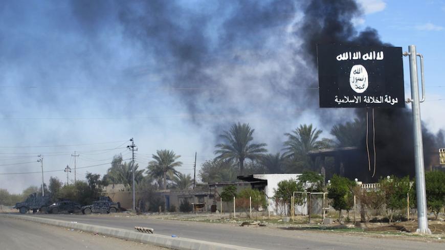 Smoke raises behind an Islamic State flag after Iraqi security forces and Shiite fighters took control of Saadiya in Diyala province from Islamist State militants, November 24, 2014. Iraqi forces said on Sunday they retook two towns north of Baghdad from Islamic State fighters, driving them from strongholds they had held for months and clearing a main road from the capital to Iran. There was no independent confirmation that the army, Shi'ite militia and Kurdish peshmerga forces had completely retaken Jalawl