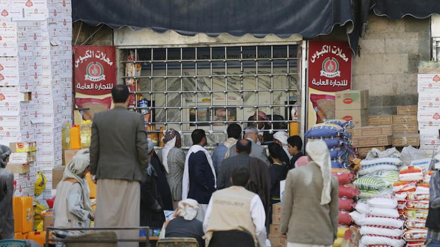 People gather outside a foodstuff store in Yemen's capital Sanaa February 29, 2016. Banks have cut credit lines for traders shipping food to war-torn Yemen, where ports have been battlegrounds and the financial system is grinding to a halt, choking vital supplies to an impoverished country that could face famine. Picture taken February 29, 2016. To match Exclusive YEMEN-FOOD/BANKS     REUTERS/Khaled Abdullah - RTS9B3R