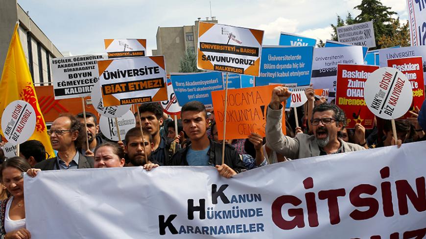Demonstrators hold signs in front of the High Education Board (YOK) during a protest against the suspension of academics from universities following a post-coup emergency decree, in Ankara, Turkey, September 22, 2016. The sign in the foreground reads "Let the emergency decrees go. We are remaining." REUTERS/Umit Bektas - RTSOY0Z