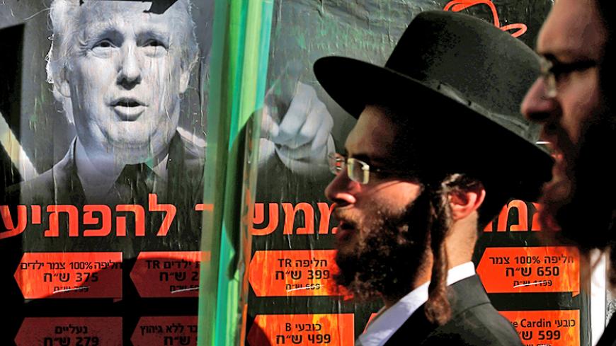 Ultra-Orthodox Jewish man walk next to a poster of Donald Trump in Jerusalem's Mea Shearim neighbourhood, October 13, 2016. REUTERS/Amir Cohen  - RTSS53C