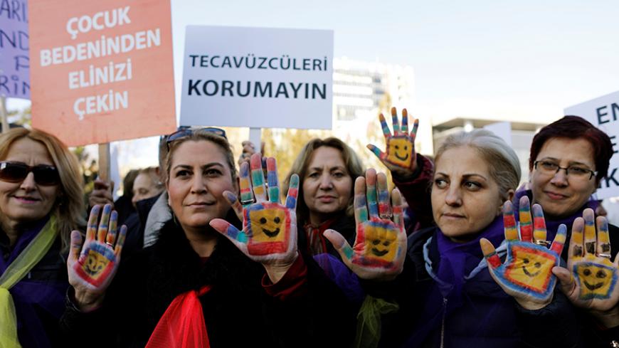 Protesters show their painted hands during a protest against a proposal, that would have allowed sentencing in cases of sexual abuse committed "without force, threat or trick" before Nov. 16, 2016 to be indefinitely postponed if the perpetrator marries the victim, in front of the Turkish Parlaiment in Ankara, Turkey, November 22, 2016. Banners read, "Keep your hands off from a child's body" (L) and "Don't protect the rapists (R)" REUTERS/Umit Bektas - RTSSRKA
