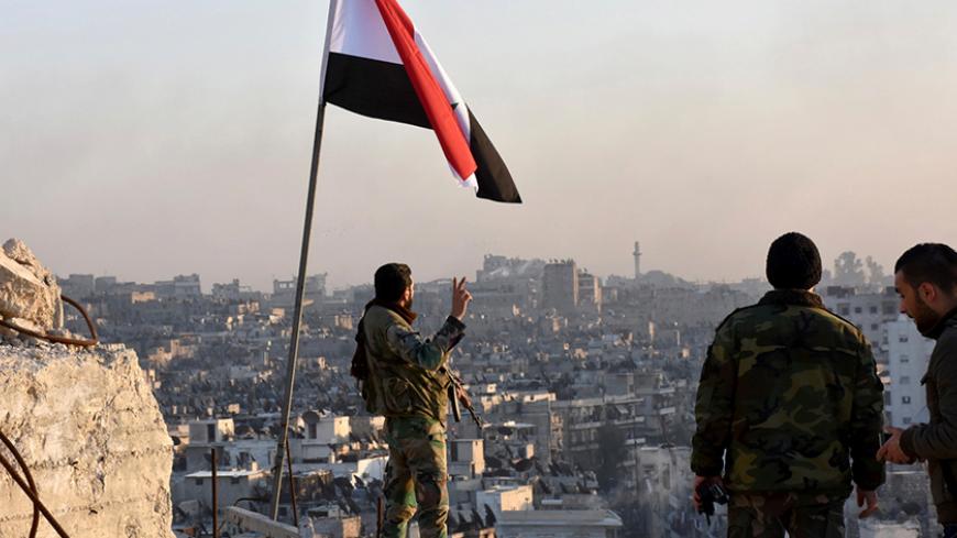 A Syrian government soldier gestures a v-sign under the Syrian national flag near a general view of eastern Aleppo after they took control of al-Sakhour neigbourhood in Aleppo, Syria in this handout picture provided by SANA on November 28, 2016. SANA/Handout via REUTERS ATTENTION EDITORS - THIS IMAGE WAS PROVIDED BY A THIRD PARTY. EDITORIAL USE ONLY. REUTERS IS UNABLE TO INDEPENDENTLY VERIFY THIS IMAGE. - RTSTSGY