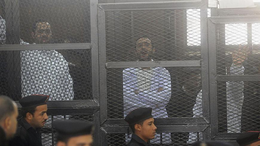 Political activists Ahmed Maher (R), Ahmed Douma (C) and Mohamed Adel, founder of 6 April movement, look on from behind bars in Abdeen court in Cairo, December 22, 2013. Three leading Egyptian activists were sentenced to three years in prison each on Sunday in a case brought over their role in recent protests, escalating a crackdown on dissent by the army-backed government. Maher, Douma and Adel are symbols of the protest movement that ignited the historic 2011 uprising against President Hosni Mubarak. Each