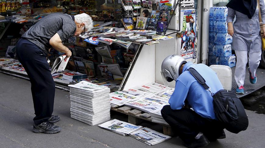 Men look at newspapers at a road side stall in central Tehran, Iran August 24, 2015.  REUTERS/Darren Staples - RTX1PH7I