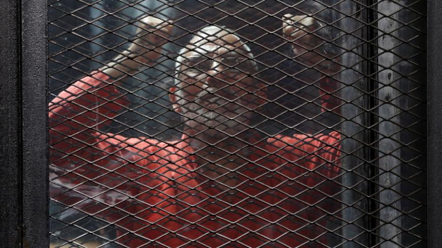 Muslim Brotherhood's leader Mohamed Badie shouts solgans against the Interior Ministery behind bars during the trial of 738 brotherhood members for their armed sit-in at Rabaa square, at a court on the outskirts of Cairo, Egypt May 31, 2016. - RTX2F137