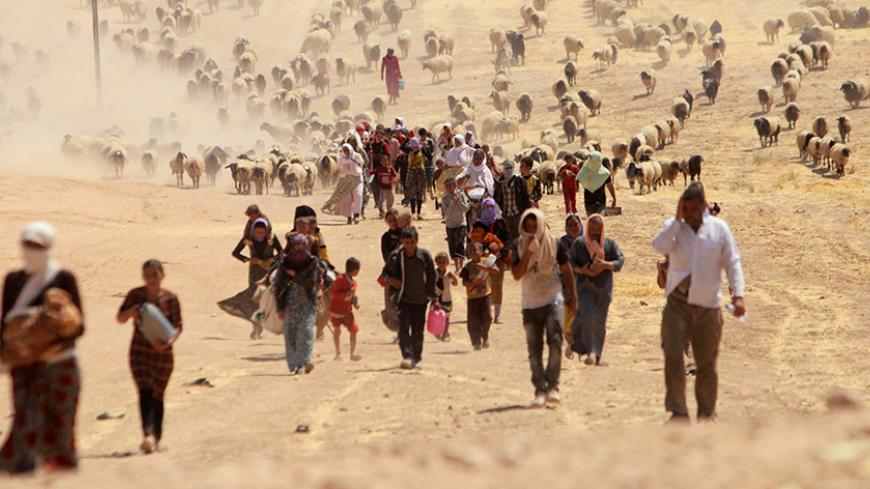 Displaced people from the minority Yazidi sect, fleeing violence from forces loyal to the Islamic State in Sinjar town, walk towards the Syrian border, on the outskirts of Sinjar mountain, near the Syrian border town of Elierbeh of Al-Hasakah Governorate August 10, 2014. REUTERS/Rodi Said/File Photo - RTX2GIYQ