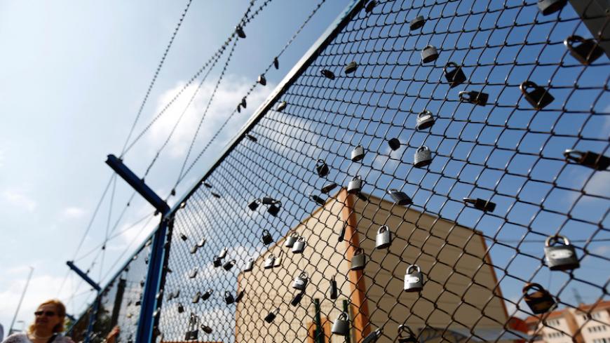 A demonstrator stands next to a fence with padlocks left by prisoners, during a protest against the arrest of three prominent activists for press freedom, in front of Metris prison in Istanbul, Turkey, June 24, 2016. REUTERS/Murad Sezer - RTX2HYKN