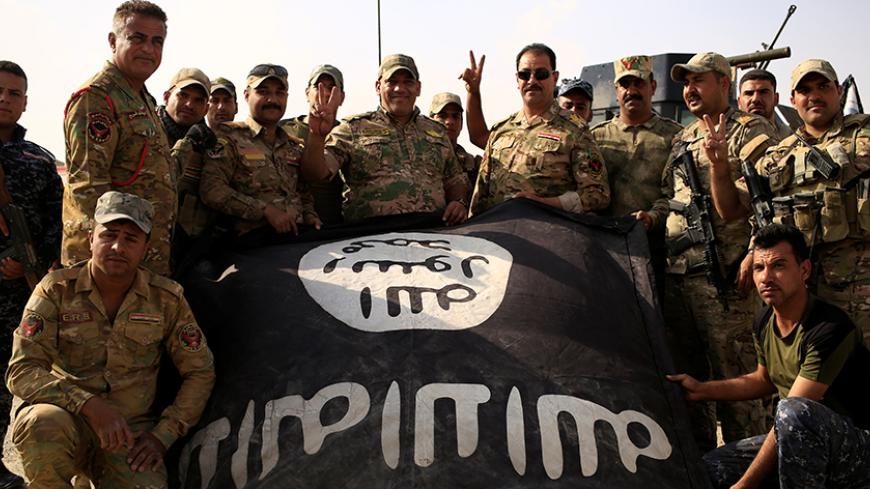 Iraqi soldiers celebrate as they pose with the Islamic State flag along a street of the town of al-Shura, which was recaptured from Islamic State (IS) on Saturday, south of Mosul, Iraq October 30, 2016. REUTERS/Zohra Bensemra - RTX2R34S