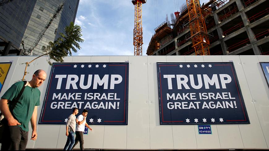 People walk past signs bearing the name of U.S. President-elect Republican Donald Trump in Tel Aviv, Israel November 14, 2016. REUTERS/Baz Ratner  - RTX2TLRV