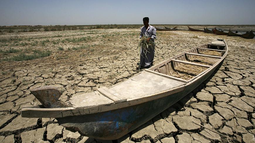 An Iraqi man walks past a canoe siting on dry, cracked earth in the Chibayish marshes near the southern Iraqi city of Nasiriyah on June 25, 2015. Marsh areas in southern Iraq have been affected since the Islamic State group started closing the gates of a dam on the Euphrates River in the central city of Ramadi, which is under the jihadist group's control. AFP PHOTO / HAIDAR HAMDANI        (Photo credit should read HAIDAR HAMDANI/AFP/Getty Images)