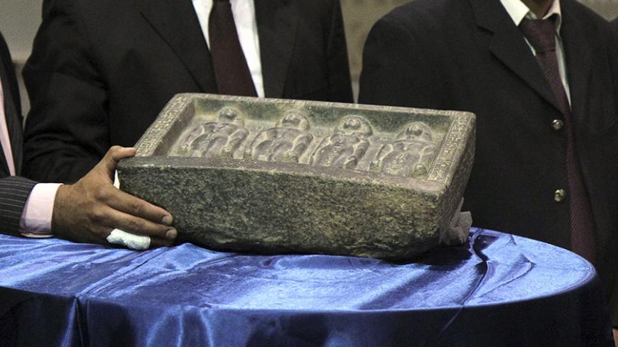 An Egyptian archaeologist shows one of the three ancient artefacts recovered from Germany during a news conference at Cairo airport, May 3, 2014. Egypt's antiquities ministry celebrated the return of three stolen ancient artefacts smuggled into Germany in 2009. Egyptian authorities held a ceremony at Cairo International Airport on Saturday to herald the recovery of the items, that were promptly placed on display as a new conference was held. Authorities believe the artefacts were bound for sale in Belgium w