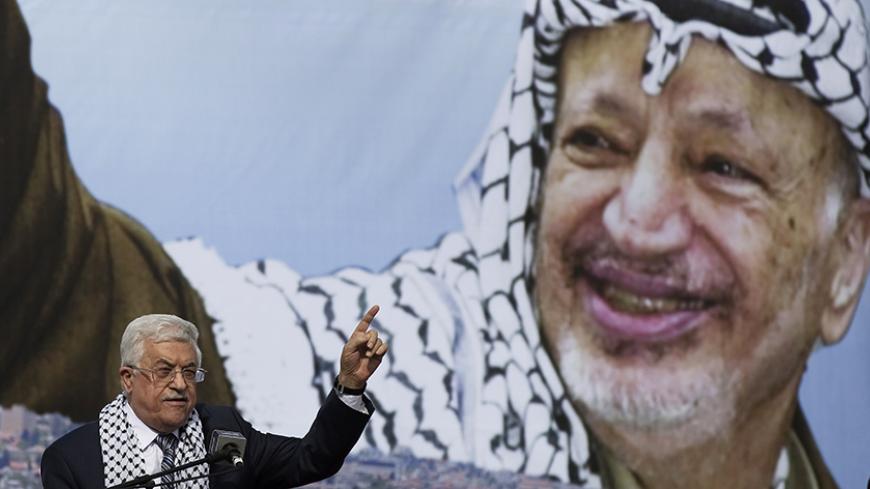 Palestinian President Mahmoud Abbas gestures beneath a poster of the late Palestinian leader Yasser Arafat, during a rally marking the tenth anniversary of Arafat's death, in the West Bank city of Ramallah November 11, 2014. Palestinian President Mahmoud Abbas on Tuesday accused his Islamist Hamas rivals of carrying out a series of bombings against officials loyal to him in Gaza last week, in a move sure to harm already floundering unity efforts. REUTERS/Finbarr O'Reilly (WEST BANK - Tags: POLITICS ANNIVERS