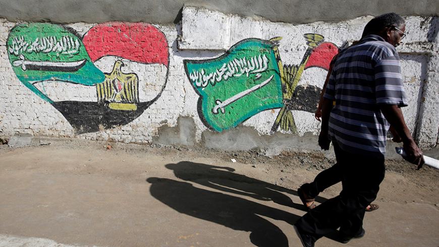 Men walk are in front of graffiti depicting relations between Egypt and Saudi Arabia in Cairo, Egypt, October 12, 2016. Picture taken October 12, 2016. REUTERS/Amr Abdallah Dalsh - RTSS9QT