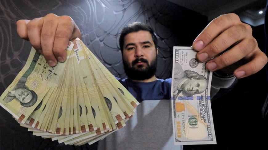 A money changer poses for the camera with a U.S  hundred dollar bill (R) and the amount being given when converting it into Iranian rials (L), at a currency exchange shop in Tehran's business district, Iran, January 20, 2016. REUTERS/Raheb Homavandi/TIMA  ATTENTION EDITORS - THIS IMAGE WAS PROVIDED BY A THIRD PARTY. FOR EDITORIAL USE ONLY. - RTX238AV