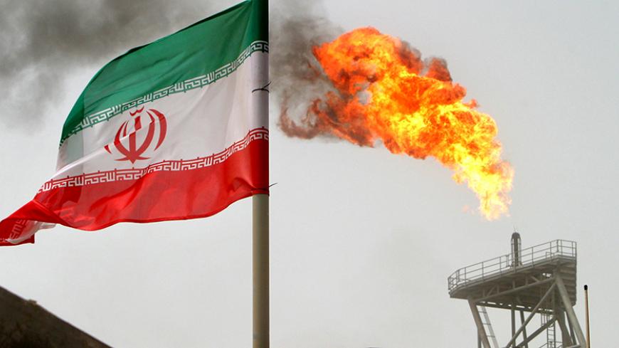A gas flare on an oil production platform in the Soroush oil fields is seen alongside an Iranian flag in the Persian Gulf, Iran, July 25, 2005.    REUTERS/Raheb Homavandi/File Photo - RTX2QOOL