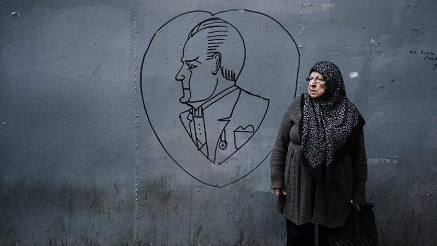 An elderly woman stands next to a graffiti showing the founder of the Turkish Republic, Mustafa Kemal Ataturk, in downtown Istanbul on October 28, 2015, a week ahead of the country's general elections on November 1. The election is crucial for the ruling Justice and Development party (AKP), which lost its majority in a June vote thanks to a strong performance by a pro-Kurdish party, scuppering president Erdogan's hopes of changing the constitution to expand his presidential powers. AFP PHOTO / DIMITAR DILKO