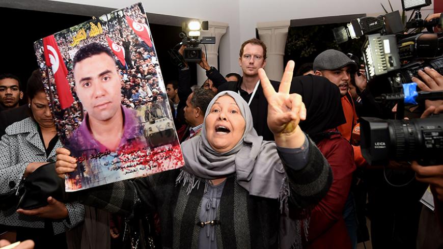 A Tunisian mother of a torture victim carries her son's portrait as she arrives for a hearing before the The Truth and Dignity Commission (IVD) in Tunis on November 17, 2016.
Victims of murder, rape and torture under successive dictatorships started testifying on live television Thursday as Tunisia -- in a rare move for the Arab world -- tries to deal with decades of abuse.

The Truth and Dignity Commission (IVD) has tracked human rights violations committed between July 1955, a year before Tunisia gained i