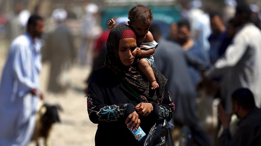 A woman carrying her infant son sells napkins at an old cattle market named "Al Emam Market" ahead of the Muslim sacrificial festival Eid al-Adha in Cairo, Egypt, September 19, 2015. Muslims across the world are preparing to celebrate the annual festival of Eid al-Adha or the Festival of Sacrifice, which marks the end of the annual haj pilgrimage, by slaughtering goats, sheep, cows and camels in commemoration of the Prophet Abraham's readiness to sacrifice his son to show obedience to Allah. REUTERS/Amr Abd
