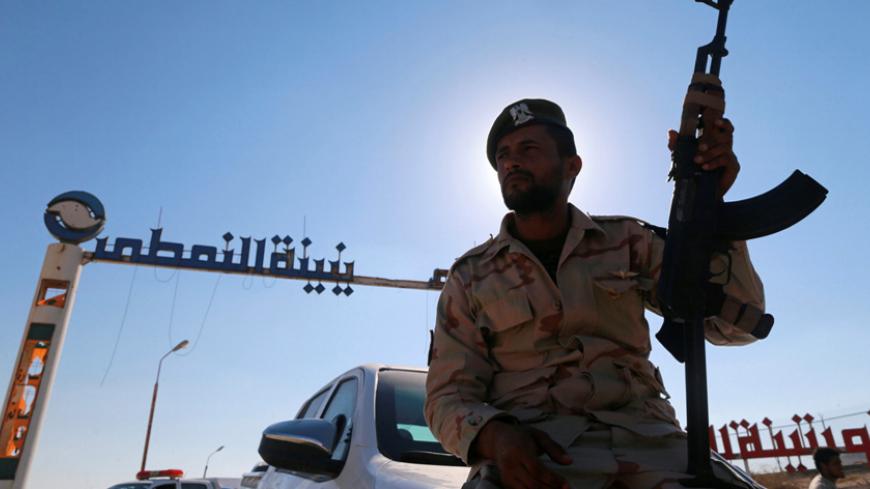 A member of Libyan forces loyal to eastern commander Khalifa Haftar holds a weapon as he sits on a car in front of the gate at Zueitina oil terminal in Zueitina, west of Benghazi, Libya September 14, 2016. Picture taken September 14, 2016. REUTERS/Esam Omran Al-Fetori - RTSNU2U