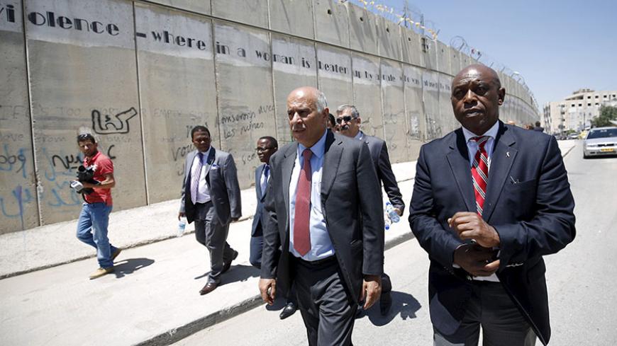 Head of the Palestinian Football Association Jibril Rajoub (2nd R) walks with anti-apartheid activist Tokyo Sexwale (R) past Israel's controversial barrier as they arrive for a news conference in the West Bank town of Al-Ram, near Jerusalem, May 7, 2015. Rajoub reinforced his call for Israel to be suspended from FIFA on Thursday, saying the Israeli Football Association was part of an "apartheid, racist government" that was damaging Palestinian soccer. REUTERS/Mohamad Torokman  - RTX1BZBF