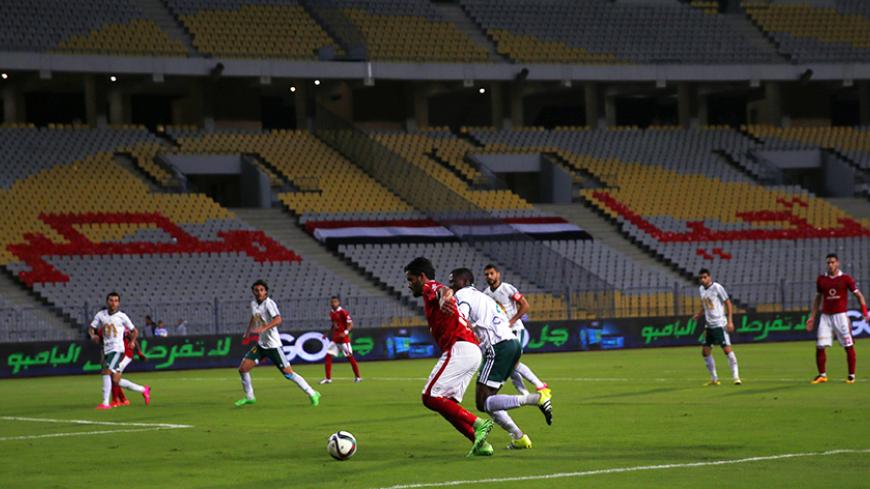 Al-Ahly's Saleh Gomaa (L) fights for the ball with Al Masry's Wilson Akakpo during their Egyptian Premier League soccer match at Borg El Arab "Army Stadium", west of the Mediterranean city of Alexandria, Egypt, February 23, 2016. The match was played without spectators due to security reasons. The arabic words on the empty seats read: "Long live Egypt."  REUTERS/Amr Abdallah Dalsh - RTX2890V