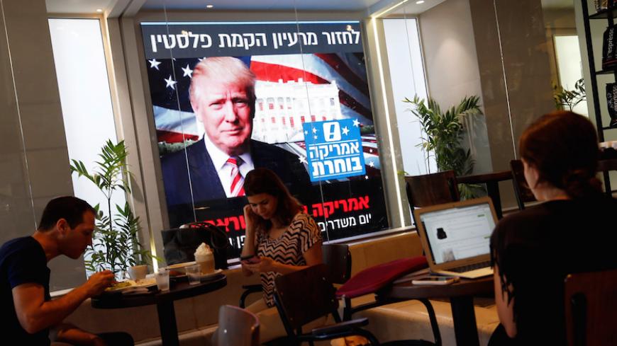 People dine at a coffee shop as an image of newly elected U.S. President Donald Trump is displayed on a monitor in Tel Aviv, Israel November 9, 2016. REUTERS/Baz Ratner - RTX2SSCC