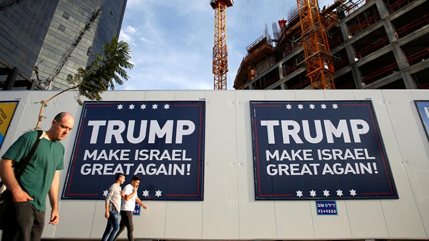 People walk past signs bearing the name of U.S. President-elect Republican Donald Trump in Tel Aviv, Israel November 14, 2016. REUTERS/Baz Ratner  - RTX2TLRV
