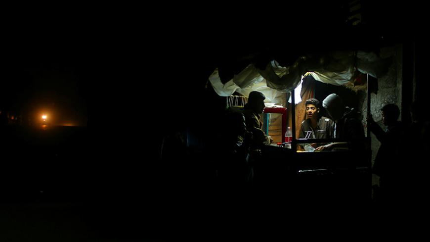 A Palestinian man sells falafel in a makeshift shop lit with a lamp powered by a battery during a power cut in Beit Lahiya in the northern Gaza Strip January 11, 2017. Picture taken January 11, 2017. REUTERS/Mohammed Salem - RTX2YNDX
