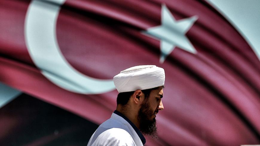 An imam passes the Turkish flag during a demonstration in support of Turkey's President Erdogan (not pictured) at the Sarachane park in Istanbul on July 19, 2016. 
Turkey has demanded the resignation of 1,577 university deans suspected of being connected with Friday's attempted coup, state-run news agency Anadolu reported July 19. The country's higher education board made the demand for deans at state and private foundation universities to resign, Anadolu said.
 / AFP / ARIS MESSINIS        (Photo credit sh