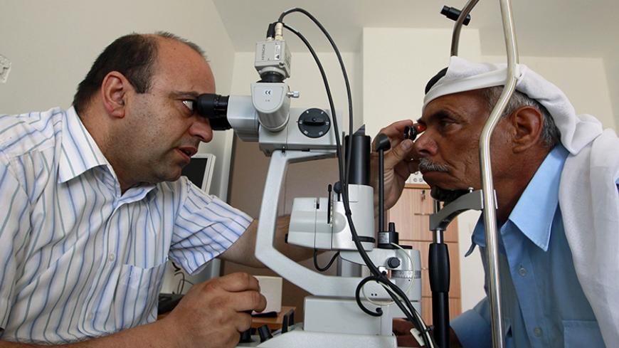 A Palestinian doctor examines the eyes of a patient at Shams medical centre in Deheishe refugee camp in the West Bank town of Bethlehem May 7, 2012. The new hospital, a stark contrast to Deheishe's general dilapidation, aims to provide services to sufferers of diabetes and hypertension to the handful of refugee camps spread around the Southern West Bank. Three generations of Palestinians displaced by the founding of Israel in 1948 know only life in United Nations refugee camps, going to schools beneath the 