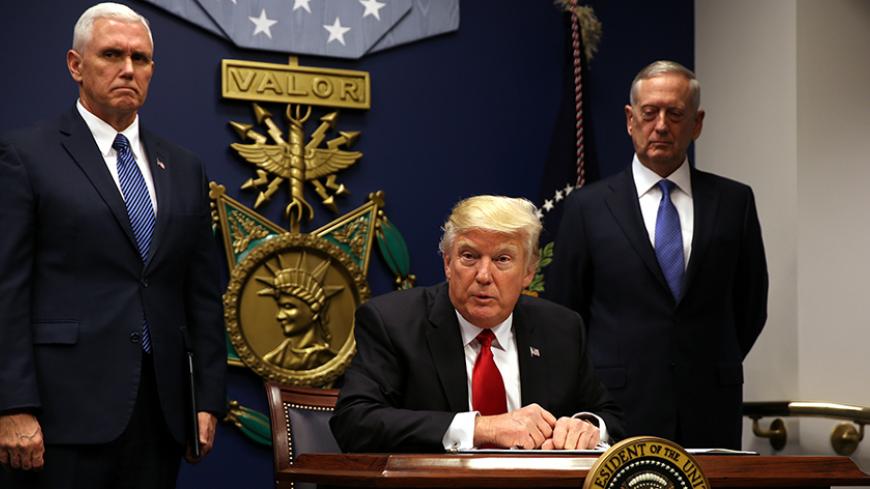 U.S. President Donald Trump signs an executive order to impose tighter vetting of travelers entering the United States, at the Pentagon in Washington, U.S., January 27, 2017. The executive order signed by Trump imposes a four-month travel ban on refugees entering the United States and a 90-day hold on travelers from Syria, Iran and five other Muslim-majority countries. Picture taken January 27, 2017. REUTERS/Carlos Barria - RTSXWM6