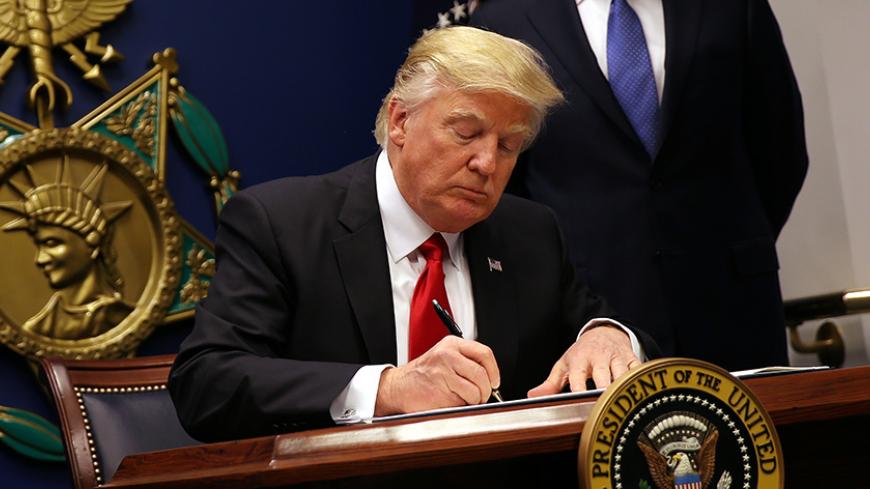 U.S. President Donald Trump signs an executive order to impose tighter vetting of travelers entering the United States, at the Pentagon in Washington, U.S., January 27, 2017. The executive order signed by Trump imposes a four-month travel ban on refugees entering the United States and a 90-day hold on travelers from Syria, Iran and five other Muslim-majority countries. Picture taken January 27, 2017. REUTERS/Carlos Barria - RTSXWMI