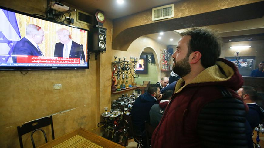 A Palestinian man watches a joint press conference by U.S. President Donald Trump and Israeli Prime Minister Benjamin Netanyahu, in a coffee shop in the West Bank city of Hebron February 15, 2017. REUTERS/Mussa Qawasma - RTSYU7C