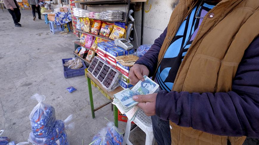 An Iranian shopkeeper counts money as he waits for customers in front of his shop at a bazar in northern Tehran January 16, 2016. REUTERS/Raheb Homavandi/TIMA  ATTENTION EDITORS - THIS IMAGE WAS PROVIDED BY A THIRD PARTY. FOR EDITORIAL USE ONLY.  - RTX22MU3