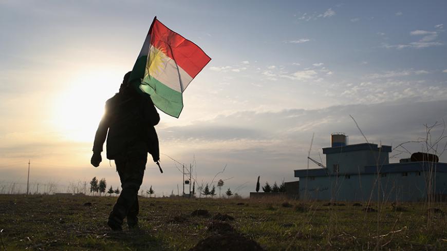 SINJAR, IRAQ - NOVEMBER 16:  A Peshmerga soldier walk to place a Kurdish flag near the frontline with ISIL on November 16, 2015 in Sinjar, Iraq. Kurdish forces, with the aid of massive U.S.-led coalition airstrikes, liberated the town from ISIL extremists, known in Arabic as Daesh, in recent days. Although many minority Yazidis celebrated the victory, their home city of Sinjar lay in almost complete ruins.  (Photo by John Moore/Getty Images)