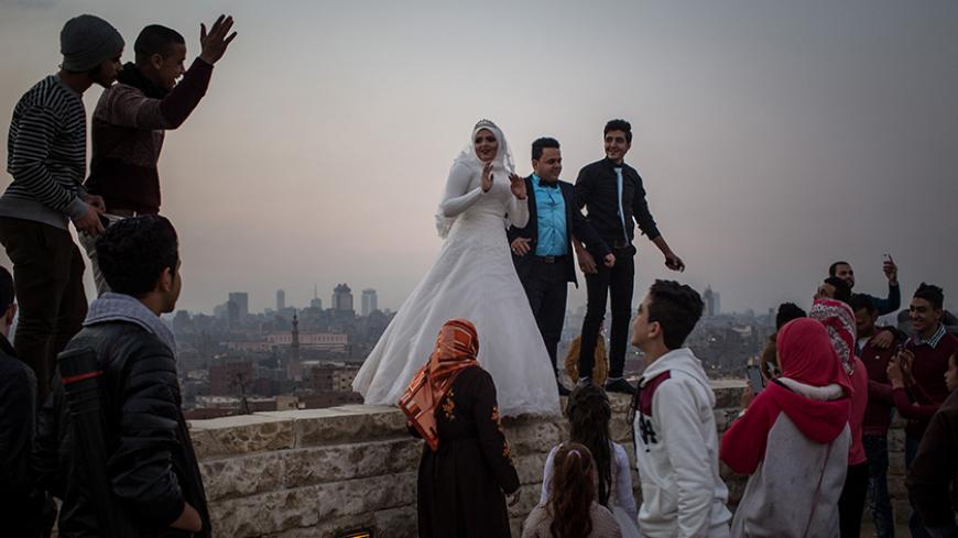 CAIRO, EGYPT - DECEMBER 10: A newlywed couple pose for wedding photos on a wall in a park overlooking Cairo on December 10, 2016 in Cairo, Egypt. Since the 2011 Arab Spring, Egyptians have been facing a crisis, the uprising brought numerous political changes, but also economic turmoil, increased terror attacks and the unravelling of the once strong tourism sector. In recent weeks Egypt has again been hit by multiple bomb blasts, the most recent killed 26 Christians inside the St Peter and St Paul Church dur