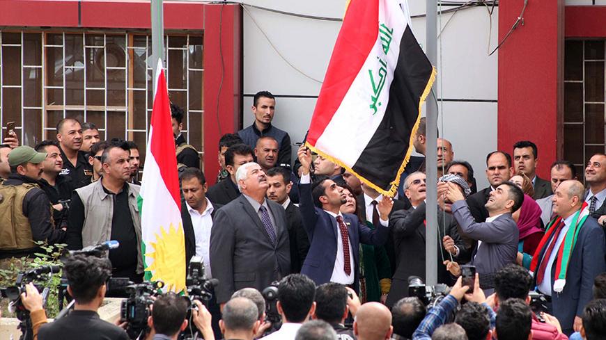 Kirkuk provincial Governor Najim al-Din Karim (C-R) raises the Iraqi flag to fly next to the Kurdish flag over a government building in the northern Iraqi city of Kirkuk on March 28, 2017.  
Provincial councillors in disputed, oil-rich Kirkuk province voted to fly the Kurdish regional flag over government buildings, a move likely to increase tensions with Baghdad. Only the 25 Kurdish provincial councillors backed the measure, while the 16 Arab and Turkmen members did not take part in the session. / AFP PHOT