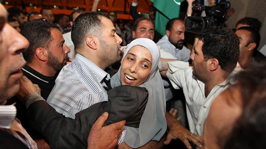 Jordanian Ahlam Tamimi (C), just released from an Israeli prison, is hugged by a relative upon her arrival at Queen Alia international airport in Amman late October 18, 2011. Tamimi had been sentenced to 16 life terms for her involvement in a suicide bombing attack on the Sbarro Pizzeria in Jerusalem in August 2001. REUTERS/Muhammad Hamed (JORDAN - Tags: POLITICS) - RTR2STMD